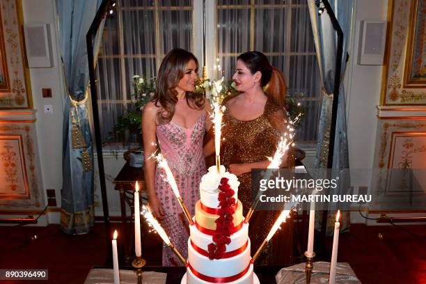 Indian billionaire Sudha Reddy stands with British actress Liz Hurley behind a cake in Paris on December 11, 2017 during a charity dinner in Reddy's...