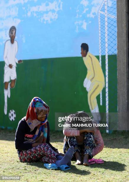 Picture taken on December 11, 2017 shows African migrants sitting outside at the Tariq Al-Matar migrant detention centre on the outskirts of the...