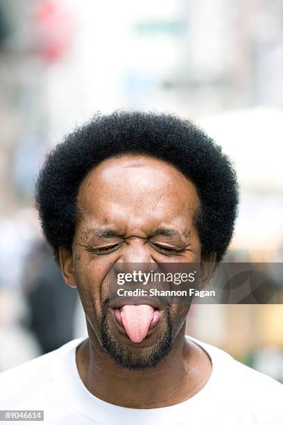 man standing in city street sticking out tongue - human tongue foto e immagini stock