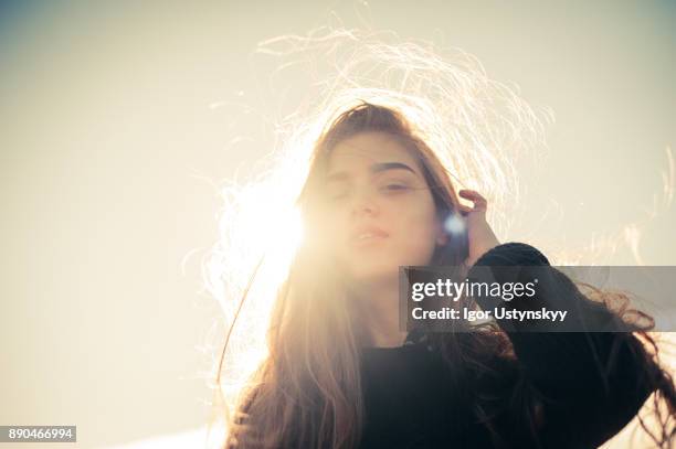 portrait of young woman tucking the hair behind the ear - back lit portrait stock pictures, royalty-free photos & images