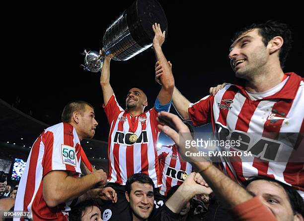 Argentinian Estudiantes de La Plata's team captain Juan Sebastian Veron holds up the trophy next to his teammates after winning the Libertadores Cup...