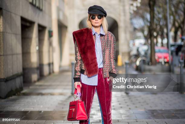 Gitta Banko wearing bordeaux velvet pants with blue stripes and a grey bomber jacket with Bordeaux pattern by Dawid Tomaszewski with a fake fur scarf...