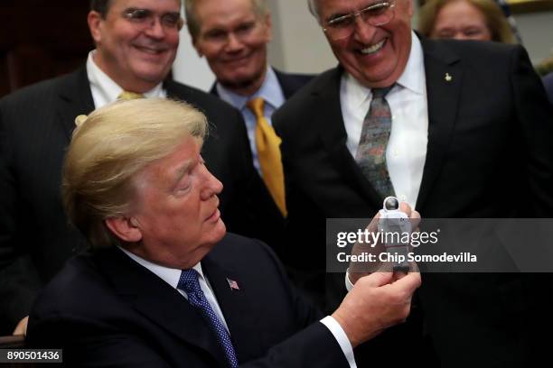 President Donald Trump holds a plastic astronaut figurine given to him by Apollo 17 astronaut and former U.S. Senator Jack Schmitt during a signing...