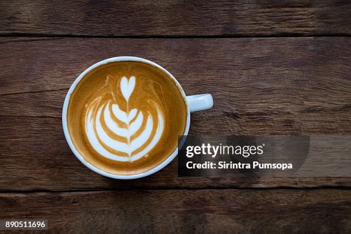A white cup of hot latte art coffee on the wooden table in coffee shop A white cup of hot latte art coffee on the wooden table in coffee shop