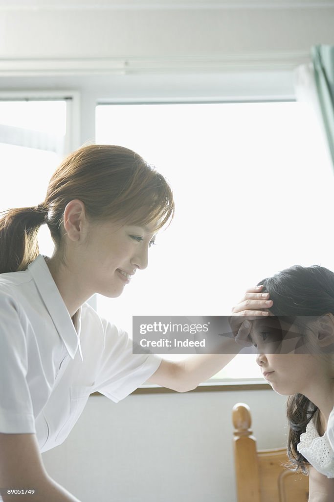 Nurse touching girl's forehead