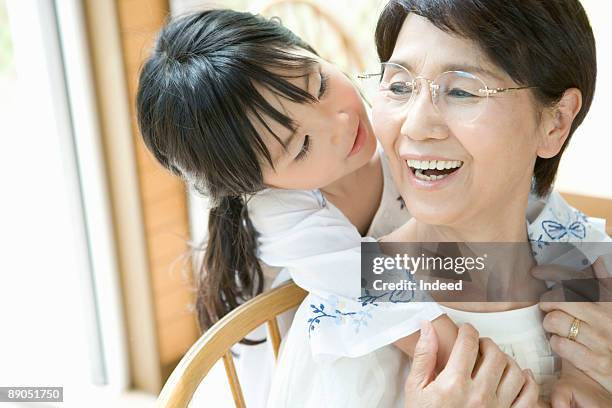 girl nestling up to her grandmother - japanese old woman stock pictures, royalty-free photos & images