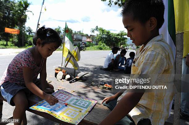 Indian children play a boardgame next to Gorkha People's Liberation Front flags on the blocked National Highway 55 in Salbari village on the...
