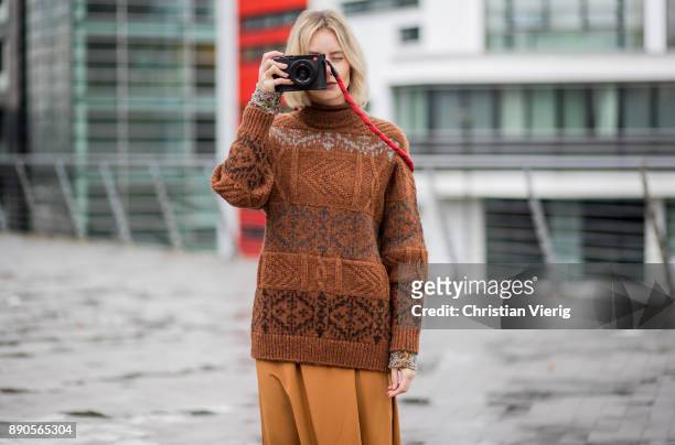 Lisa Hahnbueck taking a photo with her Leica camera wearing a brown knit Mulberry, a brown Rochas dress, golden Gianvito Rossi high heels on December...