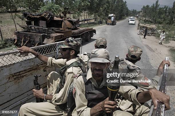 Pakistan Military patrol travel past an army tank destroyed by Taliban militants during a battle for control of the village of Sultanwas on July 16,...