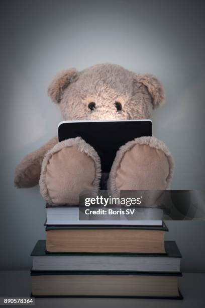 teddy bear reading an e-reader on top of thick books - screen replacement stock pictures, royalty-free photos & images