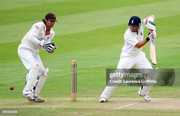 Ian Bell of Warwickshire hits out as Luke Sutton of Lancashire looks on during Day 2 of the LV County Championship Division One match between...