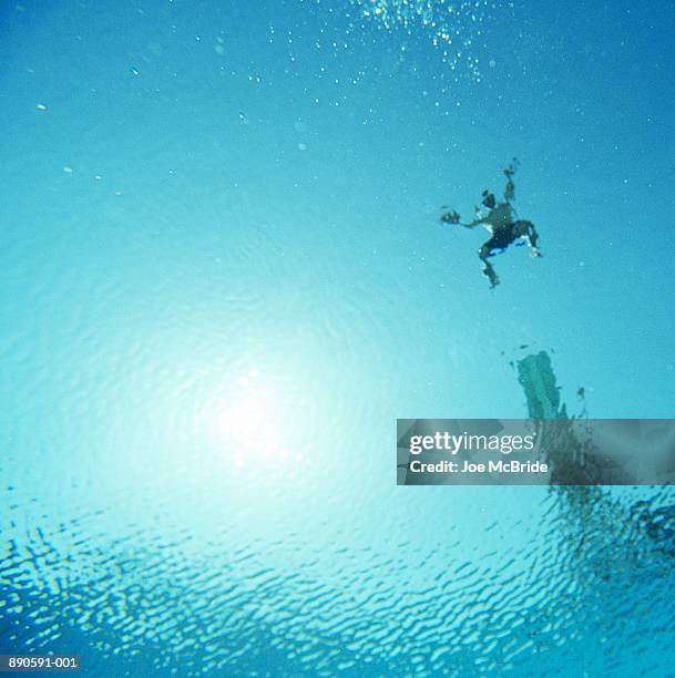 man jumping off diving board into water, underwater view - jump in pool stock-fotos und bilder