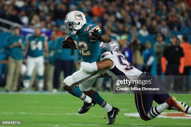 Elandon Roberts of the New England Patriots tackles Kenyan Drake of the Miami Dolphins in the first quarter at Hard Rock Stadium on December 11, 2017...