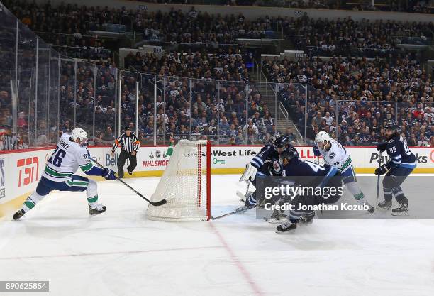 Thomas Vanek of the Vancouver Canucks centers the puck to teammate Michael Chaput as Ben Chiarot and Joel Armia of the Winnipeg Jets defends the...