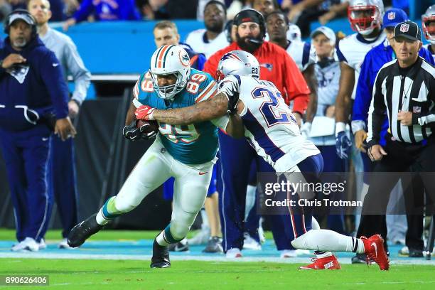 Julius Thomas of the Miami Dolphins tries to avoid the tackle from Patrick Chung of the New England Patriots during the second quarter at Hard Rock...