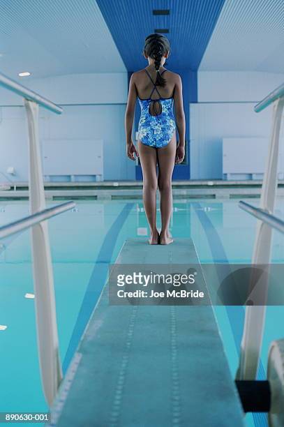 young female swimmer (8-10) on diving board, rear view - girl diving fotografías e imágenes de stock
