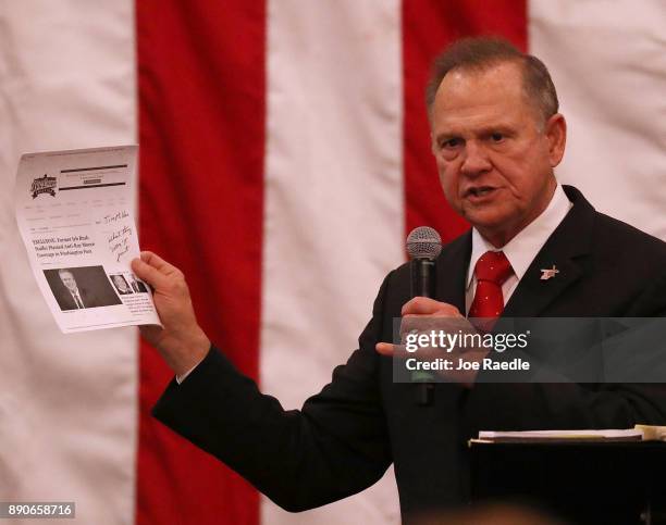 Republican Senatorial candidate Roy Moore holds up a print out of a news story as he speaks during a campaign event at Jordan's Activity Barn on...