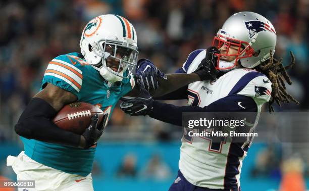 DeVante Parker of the Miami Dolphins tries to avoid the tackle of Stephon Gilmore of the New England Patriots in the third quarter at Hard Rock...