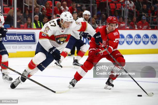 Nick Bjugstad of the Florida Panthers tries to skate past the stick of Dylan Larkin of the Detroit Red Wings at Little Caesars Arena on December 11,...