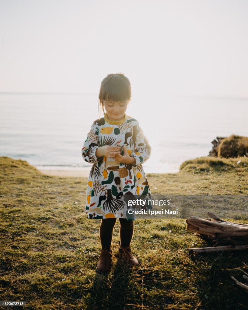 Cute toddler girl looking at her seashell collection