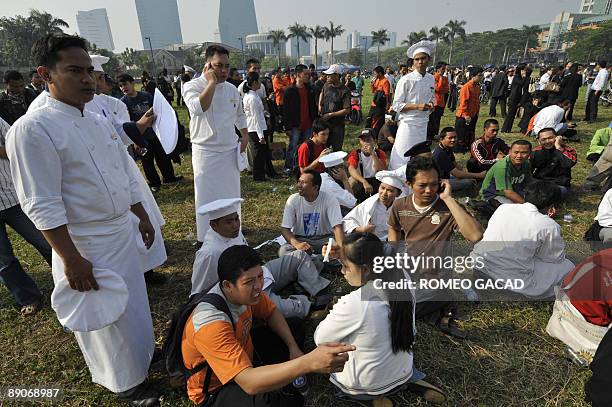 Pesonnel of Ritz-Carlton hotel are evacuated in the open field across the bombed hotel in Jakarta on July 17, 2009 after explosion hit Ritz-Carlton...