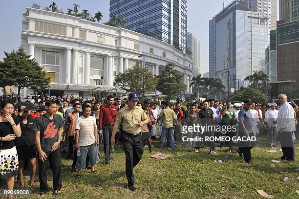 Pesonnel of Ritz-Carlton hotel are evacuated in the open field across the bombed hotel in Jakarta on July 17, 2009 after explosion hit Ritz-Carlton...