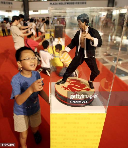 Boy takes a closer look at a statue of the late martial arts legend and movie star Bruce Lee are displayed at the Bruce Lee Collection Exhibition at...