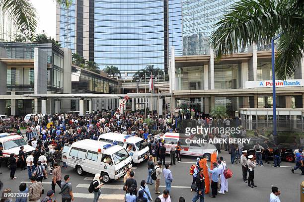 Policemen and ambulance personnel stand at the front of the JW Marriot hotel in Jakarta on July 17, 2009 after high-explosive bombs tore through the...
