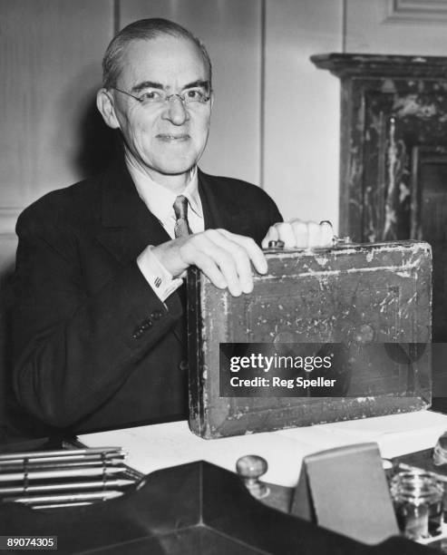 British Chancellor of the Exchequer Sir Stafford Cripps poses at the Treasury, London, with his dispatch box, the day before his budget speech to the...