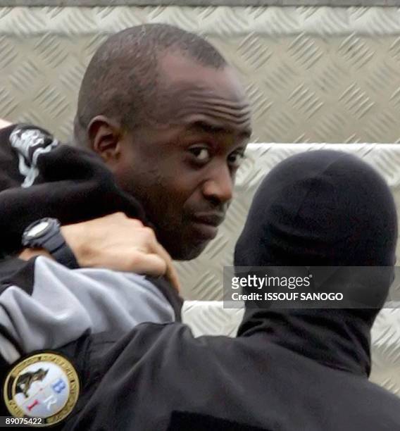 This picture taken on March 4, 2005 at Abidjan airport shows French alleged gang leader Youssouf Fofana escorted handcuffed by two plainclothes...