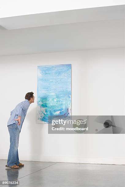 man contemplating paintings in gallery - man stand stockfoto's en -beelden