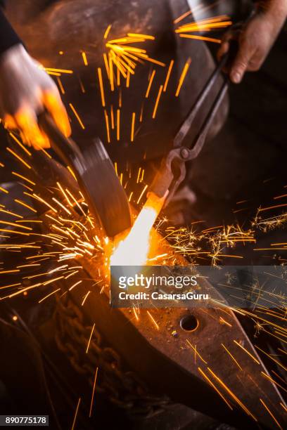 kollision mit geschmolzenes eisen mit einem hammer auf dem amboss mit funken fliegen - blacksmith sparks stock-fotos und bilder