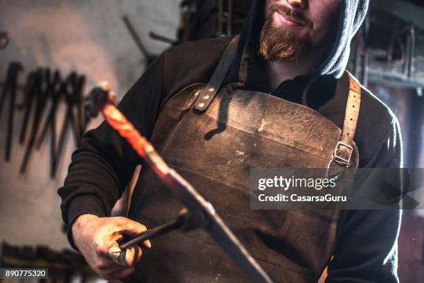 mit einem stück des glühenden eisens schmiede - schmiede stock-fotos und bilder