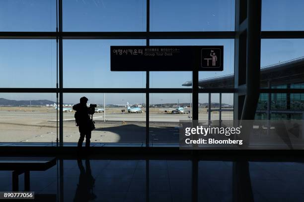 Member of the media takes a photograph of Korean Air Lines Co. Aircraft from the nearly completed terminal 2 during a media preview at Incheon...