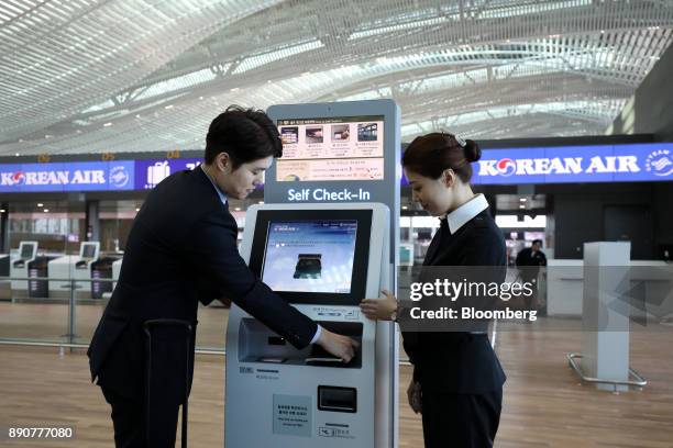 Korean Air Lines Co. Employees demonstrate a self check-in kiosk inside the nearly completed terminal 2 building during a media preview at Incheon...