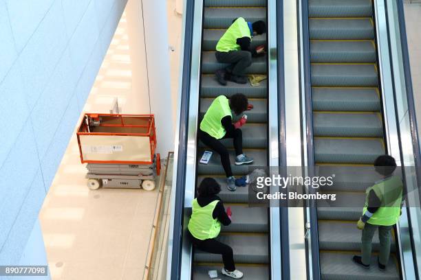Workers clean escalators inside the nearly completed terminal 2 building during a media preview at Incheon International Airport in Incheon, South...