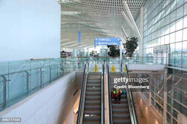 Worker cleans an escalator inside the nearly completed terminal 2 building during a media preview at Incheon International Airport in Incheon, South...