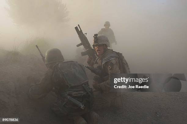 Marine with the 2nd Marine Expeditionary Brigade, RCT 2nd Battalion 8th Marines Echo Co. Along with an Afghan soldier react as dust blankets the area...