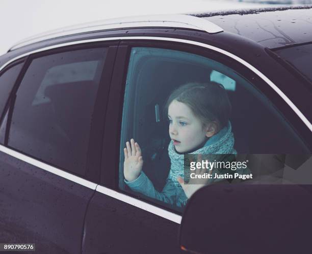 young girl looking through car window - winter car window stock-fotos und bilder