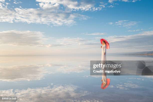 素晴らしい空の背景に傘と美しい若い女性の写真 - red dress ストックフォトと画像