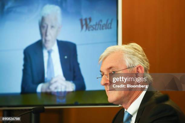 Steven Lowy, co-chief executive officer of Westfield Corp., sits as billionaire Frank Lowy, chairman, is seen on a screen during a news conference in...