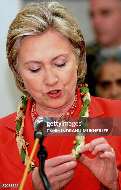 Secretary of State Hillary Rodham Clinton speaks as she holds a thread string necklace made by volunteers of the NGO Self Employed Women's...