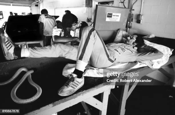 Driver Dale Earnhardt Sr. Relaxes and talks with a member of his racing crew, Jeff Hammond, in the garage prior to the start of the 1980 Firecracker...