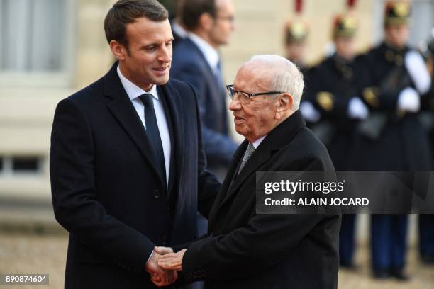 French President Emmanuel Macron greets Tunisian President Beji Caid Essebsi upon his arrival at the Elysee palace on December 12, 2017 in Paris, for...