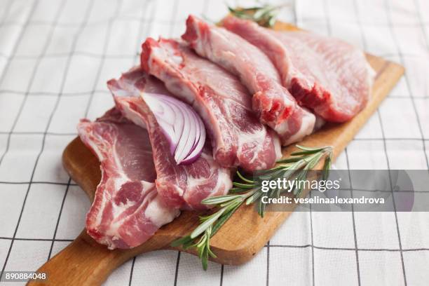 raw pork chops on a wooden chopping board - kotelett stock-fotos und bilder
