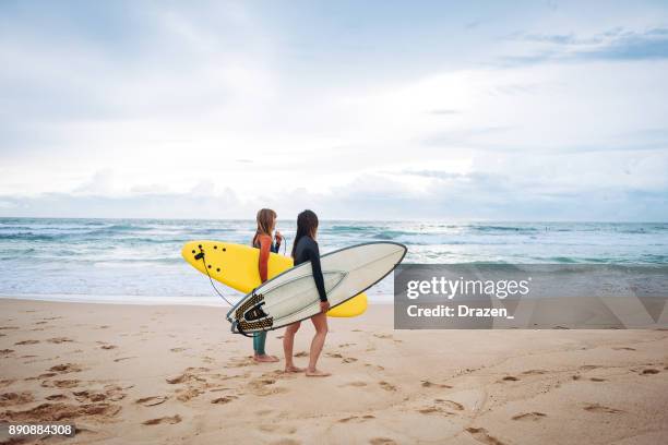 female surfers looking for waves and currents in australia - surfer stock pictures, royalty-free photos & images