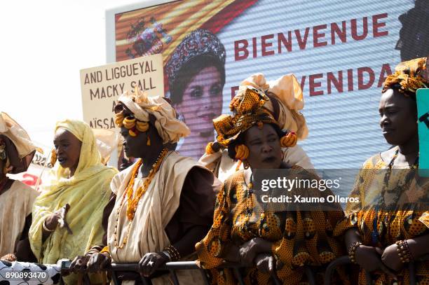 Women wait as a Letizia of Spain banner is displayed prior to her arrival to a lunch offered by first lady Marieme Faye Sall on December 12, 2017 in...