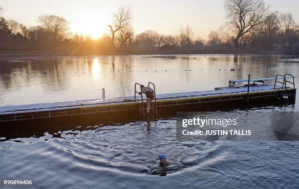 Swimmer climbs from a snow covered jetty into the ice cold water at Highgate Men's Bathing Pond, in north London on December 12 at sunrise on a...