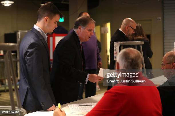 Democratic senatorial candidate Doug Jones receives his ballot as he votes at Brookwood Baptist Church on December 12, 2017 in Mountain Brook,...