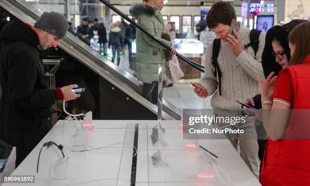 People stay around the Apple promoting table at one of shopping malls in Kyiv, Ukraine, Dec.12, 2017. IPhone X official sales started in Ukraine.